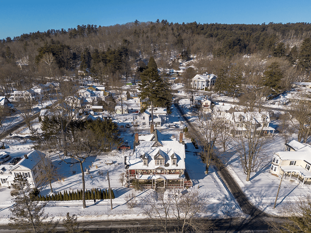 Aerial view of a snow-covered neighborhood surrounded by trees.