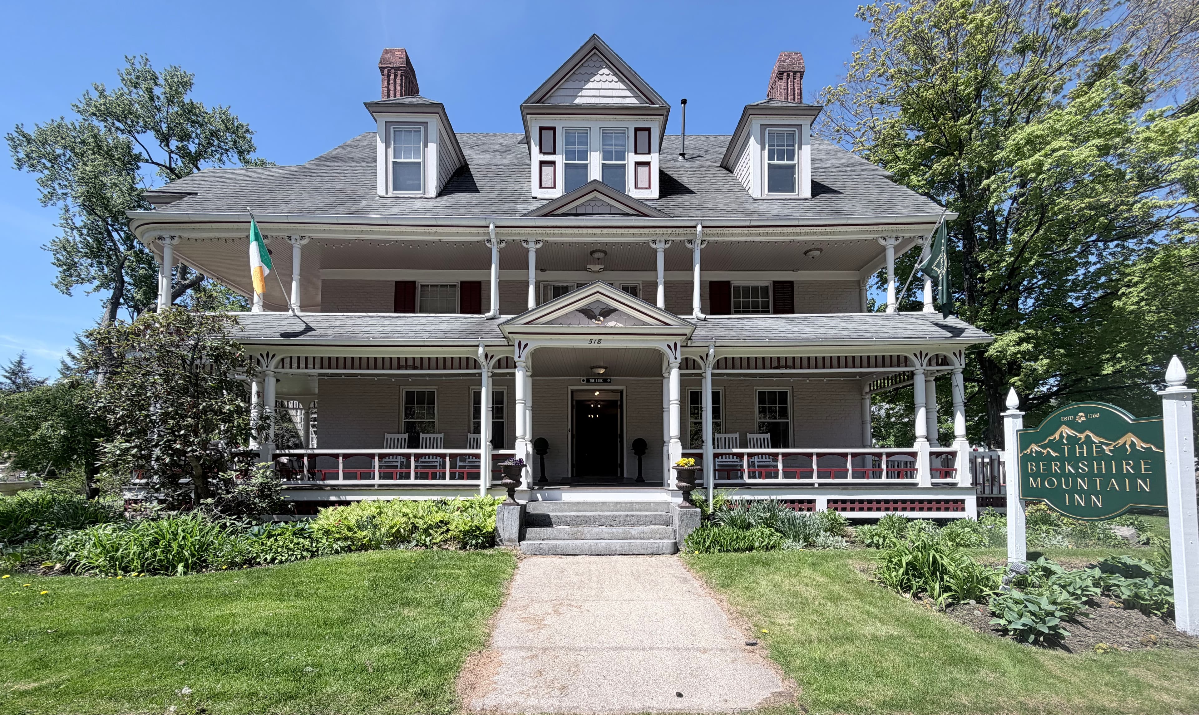 Historic Berkshire Mountain Inn with a porch, manicured lawn, and welcoming sign.